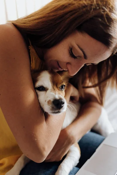 Close-up of a beautiful woman kissing her dog Jack Russell Terrier at sunset Stock Image