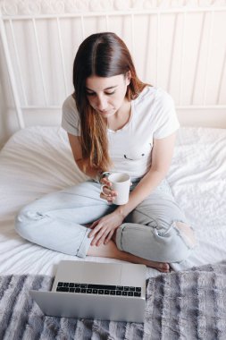 Güzel bir kadın kahve içiyor ve dizüstü bilgisayarında film izliyor.