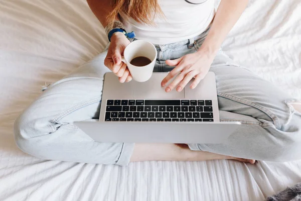 Niet-herkende jonge vrouw die koffie drinkt en op haar laptop schrijft Stockafbeelding