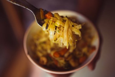 El koyu arka plan üzerinde sebze ve karides ile lezzetli erişte pikap için çatal kullanır. Asya gıda konsepti. Üstte görüntü.