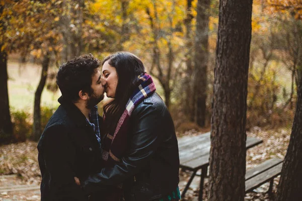 Пара влюбленных целуется осенью в осеннем лесу, наслаждаясь прекрасным днем. Пара поцелуев в красочном оранжевом и желтом парке . — стоковое фото