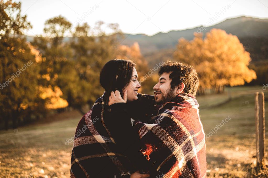 Couple in love caressing on autumn in the autumnal forest, enjoying a beautiful day. Couple kissing in the colorful orange and yellow park.