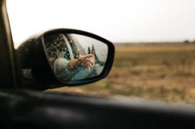 Yağmur damlalarına dokunmak. Camdan yansıyan ayna. Islak araba penceresi. Yağmur damlasını kapatın. Araba görüntüsü aynaya bak. Yağmurlu gün.