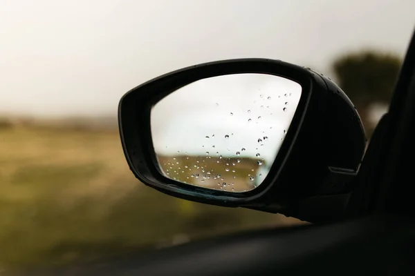 유리잔을 통해 볼 수있는 백미러. 젖은 차 창문. 빗방울을 닫습니다. 자동차의 모습 이 거울을 본다. — 스톡 사진