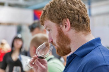Kiev, Ukrayna - 02 Haziran 2018: Tadı kırmızı şarap Kiev Şarap Festivali Kızıl saçlı Genç adam. dünyanın dört bir yanından gelen 77 winemakers iyi şarap şirketi tarafından düzenlenen festival big aldı.