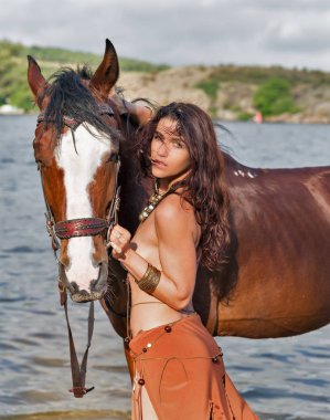 Genç Kafkas güzel çıplak Amazon kadın kırmızı atı ile kum Nehri sahilde