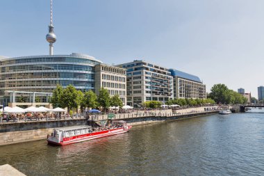 Berlin, Almanya - 14 Temmuz 2018: Berlin siluetinin Ufer promenade, televizyon kulesi, Liebknecht Köprüsü, Gdr Müzesi ve gemi ile Spree Nehri üzerinde palamarla. Başkenti ve en büyük Alman şehri Berlin'dir.