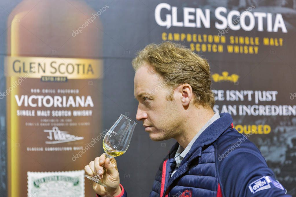 KIEV, UKRAINE - OCTOBER 20, 2018: Man tasting Glen Scotia Scotch highland single malt whisky at booth of 4th Ukrainian Whisky Dram Festival organized by Good Wine company in Artistic Arsenal.