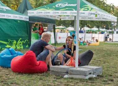 Kiev, Ukrayna - 06 Temmuz 2018: bir nargile sırasında ziyaret Ulusal Expocenter Atlas hafta sonu müzik festivali açık hava müzik konserine genç müzik hayranları çift duman.