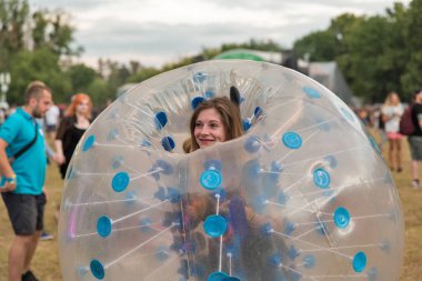 KIEV, UKRAINE - JULY 08, 2018: Young woman have fun inside of the transparent plastic spheres body bumper ball at Atlas Weekend Festival in National Expocenter. It is annual music and arts festival.