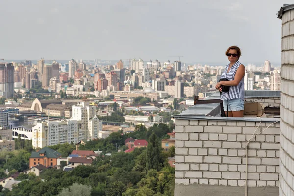 Kiev, Ukrayna Hava cityscape ile yüksek bir binanın çatısında beyaz orta yaşlı tabaklanmış kadın durumda.