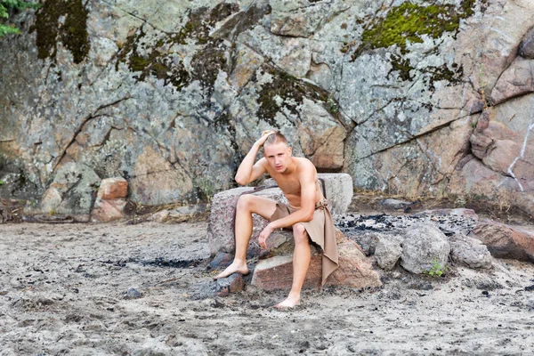 Guy in loincloth op de achtergrond van de rotsen — Stockfoto