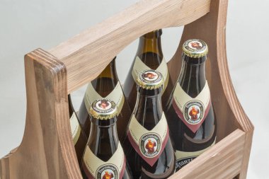 KYIV, UKRAINE - 27 Ekim 2019: Alman Franziskaner koyu Weissbier şişeleri ahşap sepetteki beyaz arka plana yakın çekim. Münih, Almanya 'da 1397' den beri buğday koyu ve beyaz bira demlenmiştir..