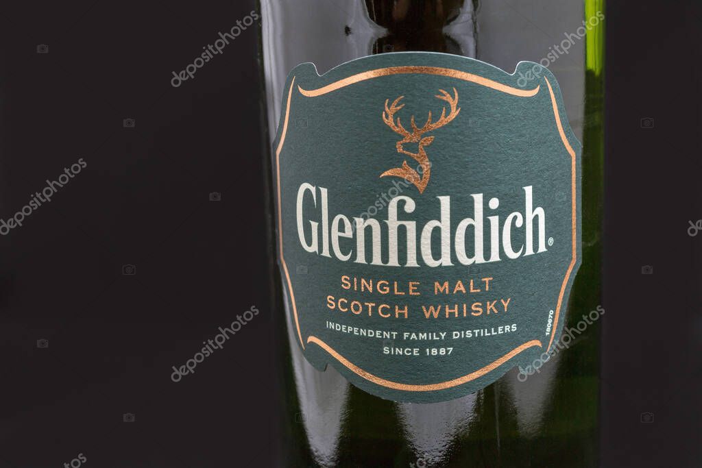 KYIV, UKRAINE - AUGUST 17, 2019: Bottle of Glenfiddich Scotch single malt whisky closeup against black. Glenfiddich means 'Valley of the Deer' in Gaelic, reason for the stag symbol on the bottle.