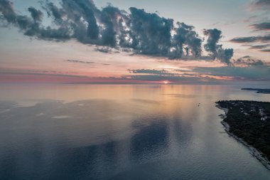 Hırvatistan 'ın Istria kıyısında, sakin Adriyatik Denizi üzerindeki dramatik akşam bulutları, sudaki yumuşak yansımalarla.