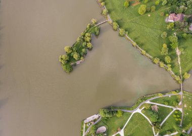 Nagykanizsa yakınlarındaki huzurlu Macaristan kırsalında sakin bir kayık gölü üzerinde hava aracı manzarası. Bereketli yeşil bitki örtüsü, ağlayan söğütler ve kırsal evler cennet gibi deniz manzarası yaratır..