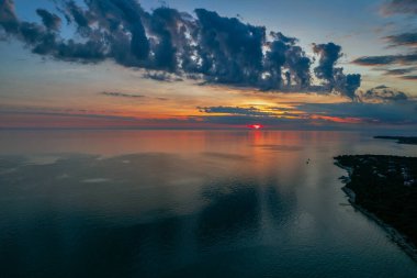 Hırvatistan 'ın Istria kıyısında, sakin Adriyatik Denizi üzerindeki dramatik akşam bulutları, sudaki yumuşak yansımalarla.