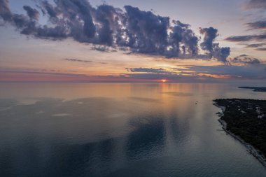 Hırvatistan 'ın Istria kıyısında, sakin Adriyatik Denizi üzerindeki dramatik akşam bulutları, sudaki yumuşak yansımalarla.