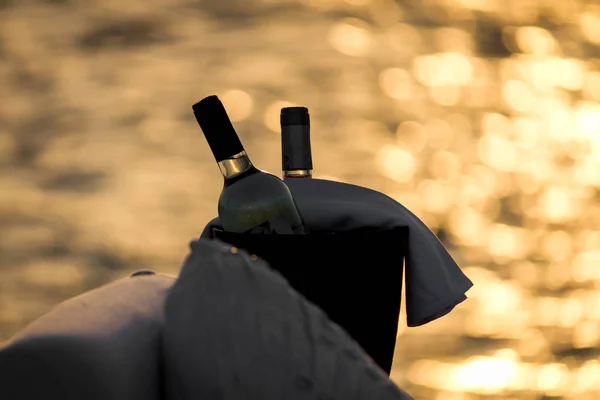 Backlight of two bottles of wine at the terrace at sunset with sea background and bokeh
