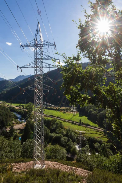 太陽と草原 道路のある風景の照明と金属送電線鉄塔 — ストック写真