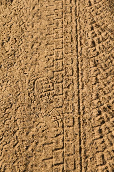 在尘土飞扬的土路上滚的车辆几何脚印和人类的足迹 — 图库照片