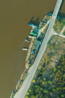 Havadan, İHA 'dan, nehirdeki teknelerin otoparkına ve baharda çamurlu suya bak..