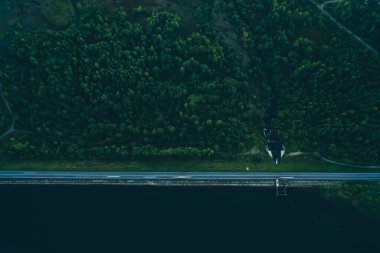 İnsansız hava aracının görüntüsü. Barajın üstünden bak. Barajda yol var. Yol. Yeşil orman. Yaz. İyi akşamlar. Yeşil.