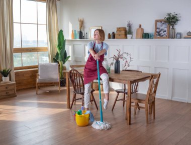 Kadınlar odadaki paspasla yerleri silip temizler.