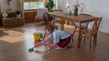 Kadınlar odadaki paspasla yerleri silip temizler.