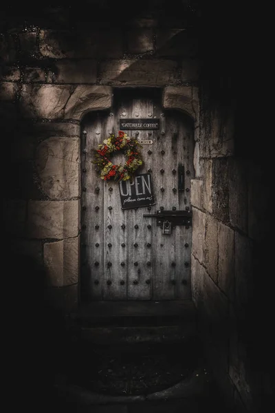 YORK, ENGLAND, DECEMBER 12, 2018: Creepy old strong wooden door with a padlock, a colorful Christmas ornament and a sign which invites you to come inside. — Stock Photo, Image