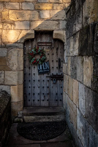 YORK, ENGLAND, DECEMBER 12, 2018: Creepy old strong wooden door with a padlock, a colorful Christmas ornament and a sign which invites you to come inside.