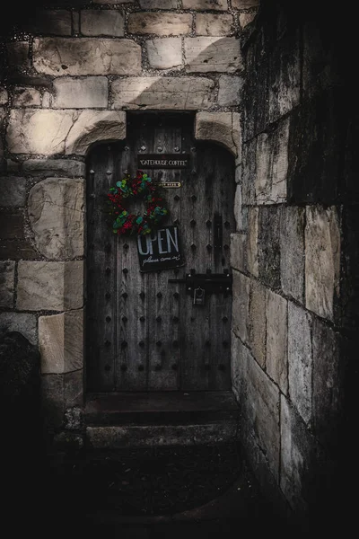 York, Anglia, 12 grudnia 2018: straszne stare silne drewniane drzwi z kłódki, kolorowy ornament Christmas i znak, który zaprasza do wewnątrz. — Zdjęcie stockowe