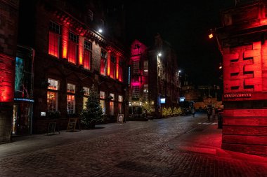 Edinburgh, İskoçya 13 Aralık 2018: Victoria St. ve Ramsay Lane boyunca yürüyen insanlar, geceleri arka planda kale ile renkli ışıklı binalarla çevrili.