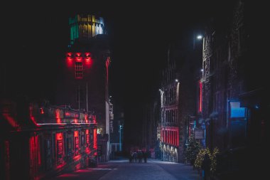Edinburgh, İskoçya 13 Aralık 2018: Victoria St. gecesi renkli ışıklı binalarla çevrili bir gecede daire içinde toplanan insanlar. Sert ışık ve karanlığın karışımı.