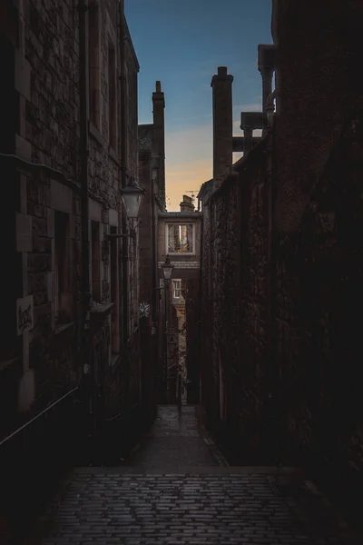 Narrow European alley, surrounded by bricks and cobblestone. Illuminated only with weak light from sunrise. Concept of scared or being alone and frightened — Stock Photo, Image