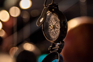 Arka planda ışıklar ve yansımalarla asılı güzel bir pusula. Kaybolma kavramı, özgürlük ve mutluluk arayışı..