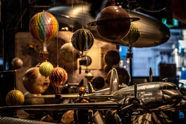 Muchos juguetes viejos junto con pequeños globos de aire caliente colgando, aviones y dirigibles suavemente iluminados. Concepto de recuerdos nostálgicos. — Foto de Stock