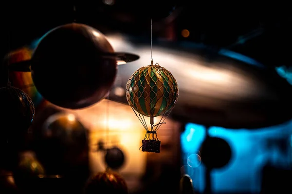 背景に惑星や飛行船がぶら下がっている小さな熱気球のおもちゃの美しいボケ。科学への驚きの懐かしい思い出の概念. — ストック写真