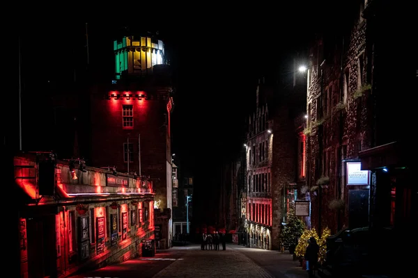 Edinburgh, İskoçya 13 Aralık 2018: Victoria St. gecesi renkli ışıklı binalarla çevrili bir gecede daire içinde toplanan insanlar. Sert ışık ve karanlığın karışımı. — Stok fotoğraf