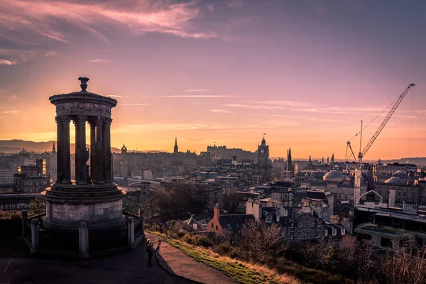 Edinburgh, İskoçya 14 Aralık 2018: Edinburgh Şatosu ve Kuzey Köprüsü de dahil olmak üzere Edinburgh şehir merkezinin arkasındaki Dugald Stewart Anıtı 'nda güzel bir günbatımı