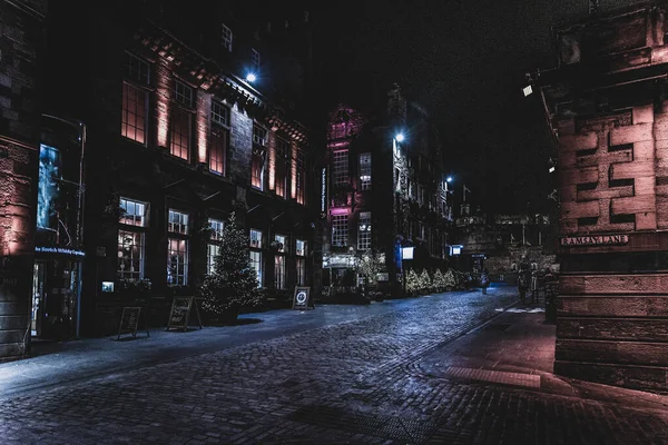 Edinburgh, İskoçya 13 Aralık 2018: Victoria St. ve Ramsay Lane boyunca yürüyen insanlar, geceleri arka planda kale ile renkli ışıklı binalarla çevrili.