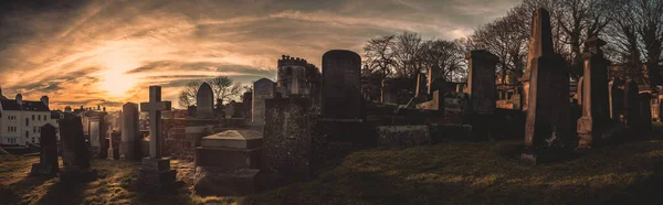 EDINBURGH, ÉCOSSE 14 DÉCEMBRE 2018 : pierres tombales anciennes, désolées et grincheuses, monuments commémoratifs et pierres tombales dans le cimetière, le soleil se levant au cimetière de New Calton — Photo