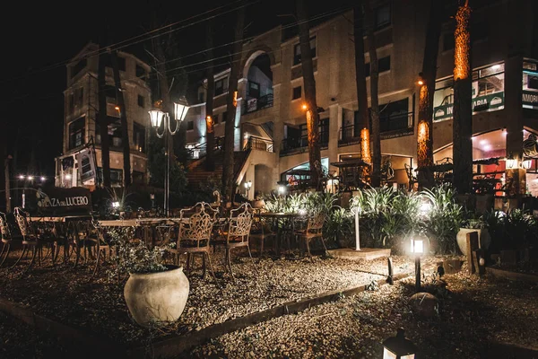 Night scene of an elegant outdoor bar illuminated by small lamps among the trees and plants — Stock Photo, Image