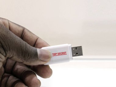 Beyaz zemin üzerinde bir Usb flash sürücü-kırmızı üst gizli uyarı etiketi ile tutan el