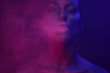 Neon Vape parti, gece hayatı. Güzel seksi duman exhaling kadınla gece kulübü neon, göz alıcı makyaj vaping. Kız yasaktır Buharlaştırıcı Club. Mavi mistik duman