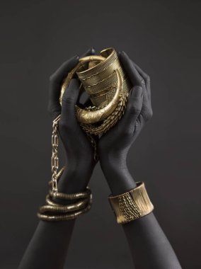 Altın takı ile kadının el Siyah. Oriental bilezik bir siyah el boyalı. Altın takı ve lüks aksesuarları siyah arka plan üzerinde. Yüksek moda sanat kavramı 