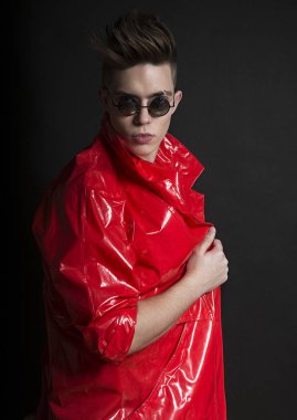 Genç adamın portresi. Moda kırmızı Lake yağmurluk şık yakışıklı seksi adam, yakın çekim yüz ile yuvarlak güneş gözlüğü. Street Style. Trendy genç erkek bak. Adam kırmızı açmada.  
