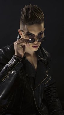 Yuvarlak gözlüklü genç adamın portresi. Siyah deri moda rocker tarzı ceket, yakın çekim yüz şık yakışıklı seksi çocuk. Rocker, street Style. Trendy rock 'n' roll erkek bak