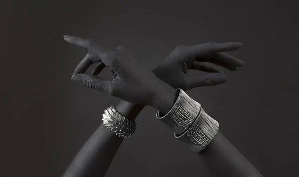 Black woman\'s hands with many different Silver jewelry. Oriental Bracelets on a black hand. Silver Jewelry and luxury accessories on black background. High Fashion art concept