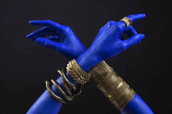 Blå kvinnas händer med indiska guld smycken. Orientaliska armband Stockbild
